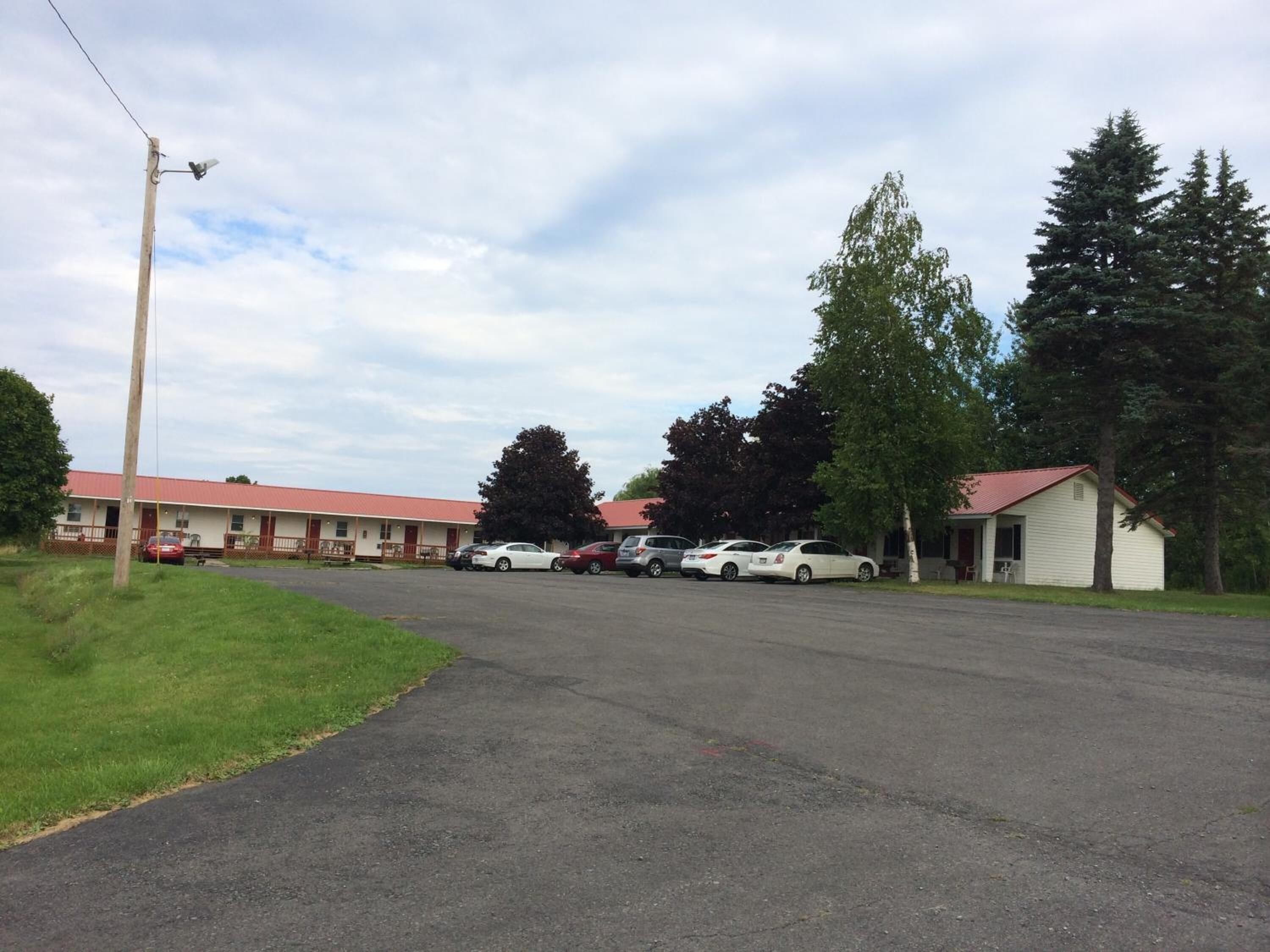 A motel with multiple rooms, a parking lot, and a small building.