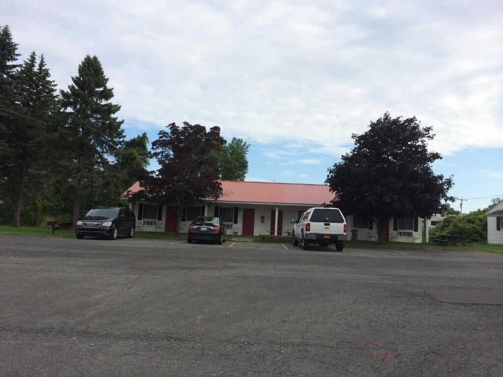 A building with a red roof and a parking lot with three vehicles.