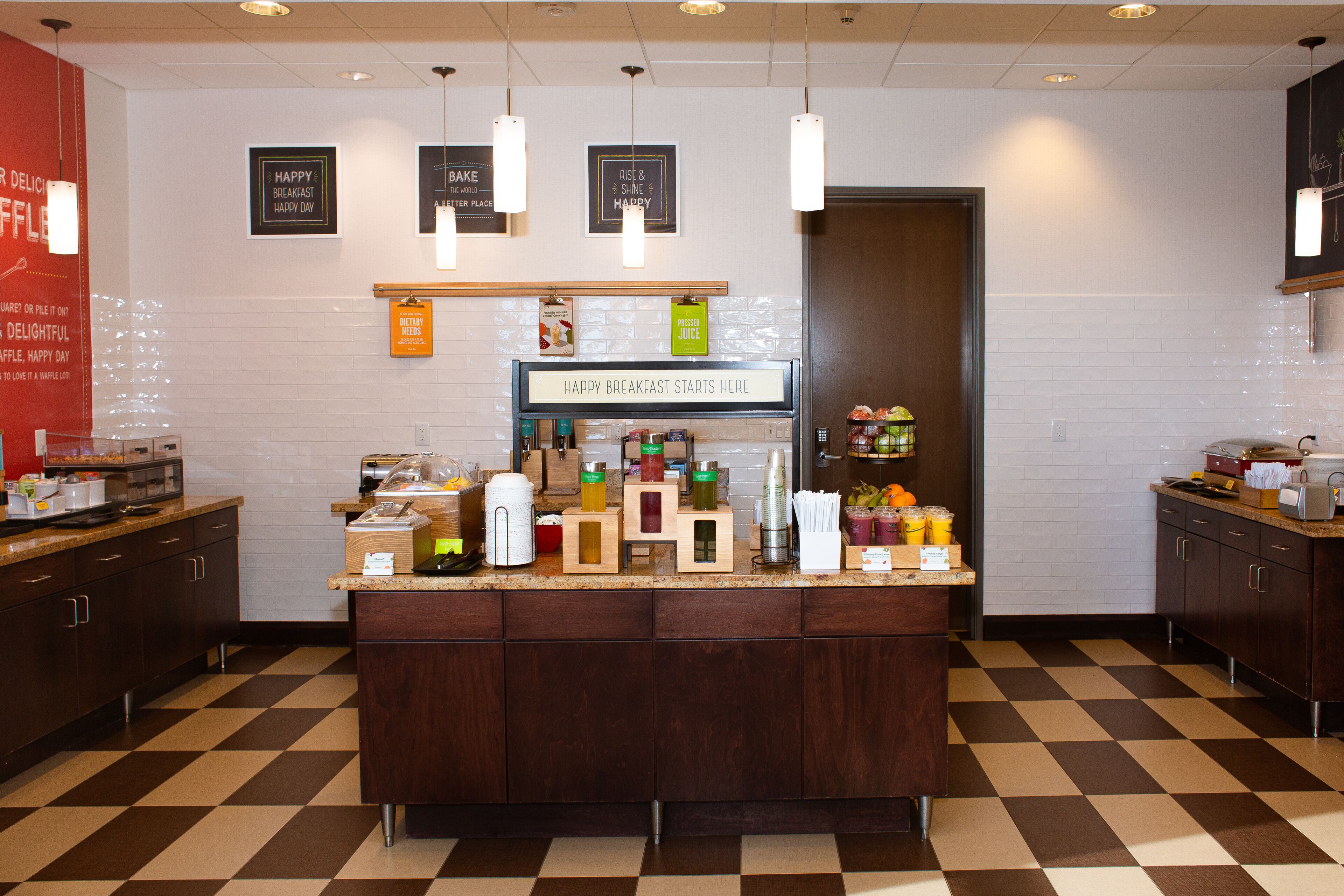 A breakfast bar with a sign that says "Happy Breakfast Starts Here" and various food items and condiments on display.