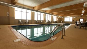 Een binnenzwembad, ligstoelen bij het zwembad