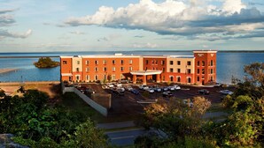 A multi-story hotel with a parking lot and a view of a lake. - Hampton Inn Marquette/Waterfront (Marquette)