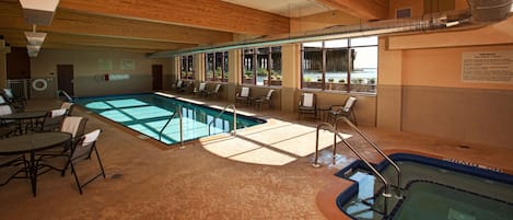A pool area with a hot tub, lounge chairs, and a sign indicating no lifeguard on duty.