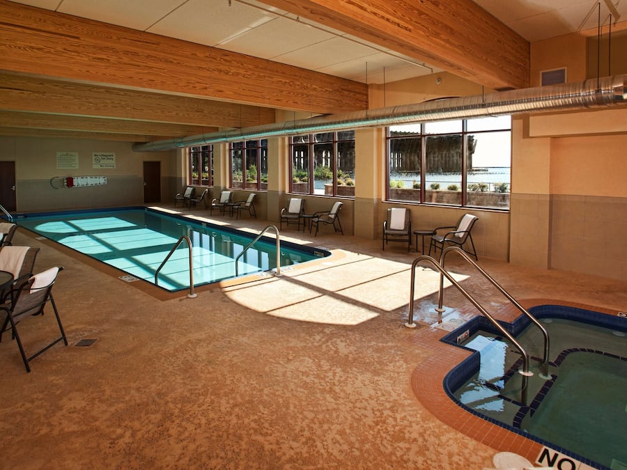 Et poolområde med jacuzzi, liggestole og et skilt, der angiver, at der ikke er livredder på vagt.