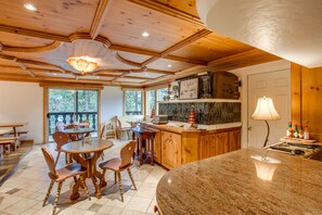 A wooden interior with a kitchen island, dining area, and large windows.