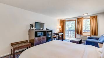 A hotel room with a large bed, a desk with a computer, a television, and a seating area with a couch and chairs.