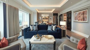 Ein modernes Wohnzimmer mit einem dunkelblauen Sofa, beigen Sesseln und einem Couchtisch aus Marmor.