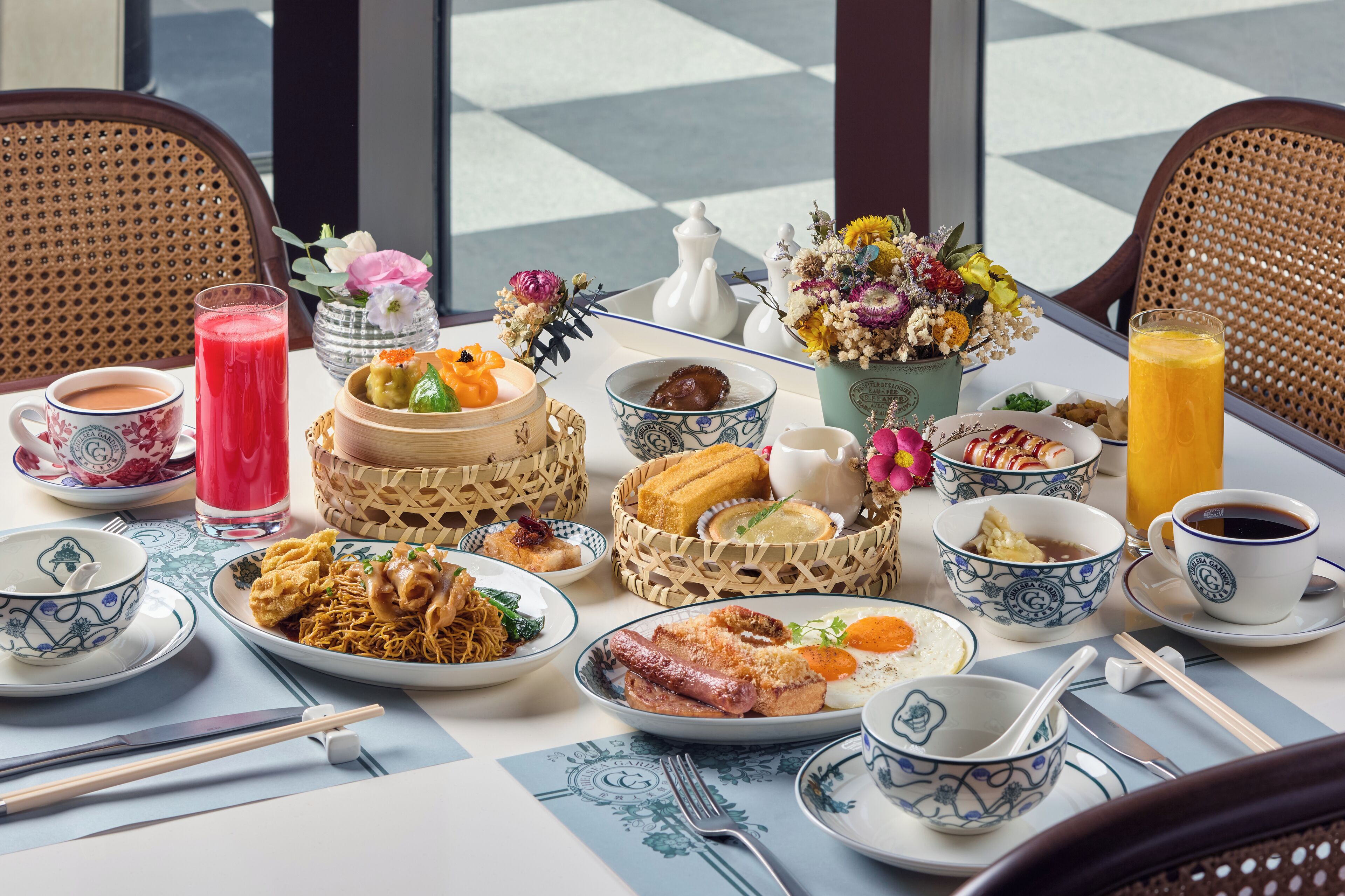 Una mesa dispuesta con diferentes platos, incluyendo fideos, carne y un frutero, además de tazas de té y jugo.
