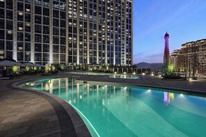 Una piscina al aire libre, sombrillas, sillones reclinables de piscina