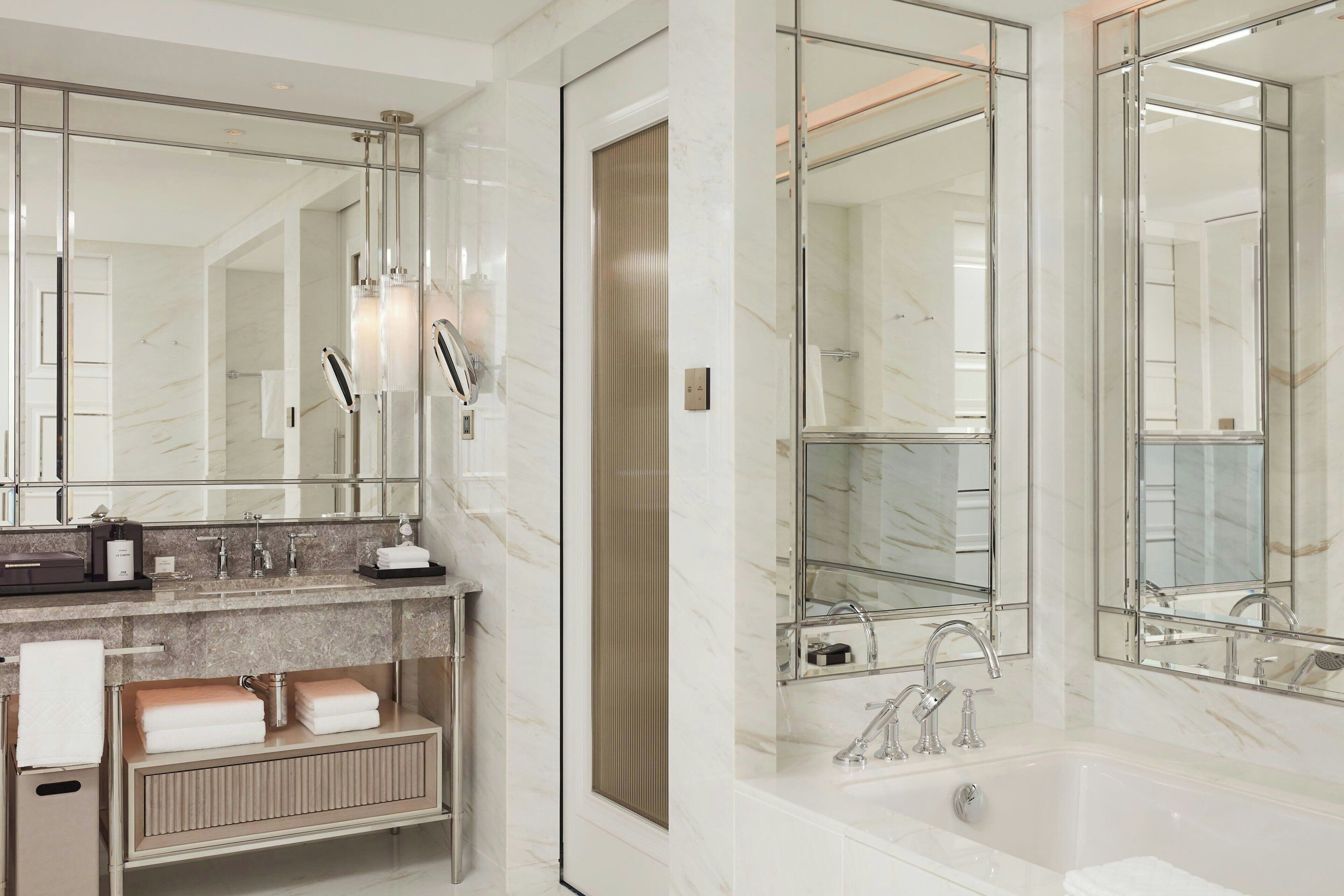Un baño moderno con un espejo grande, una bañera y un tocador con toallero.