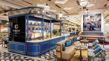 A bar area with a blue and gold color scheme, a seating area with sofas and armchairs, and a large poster of a bear on the wall.