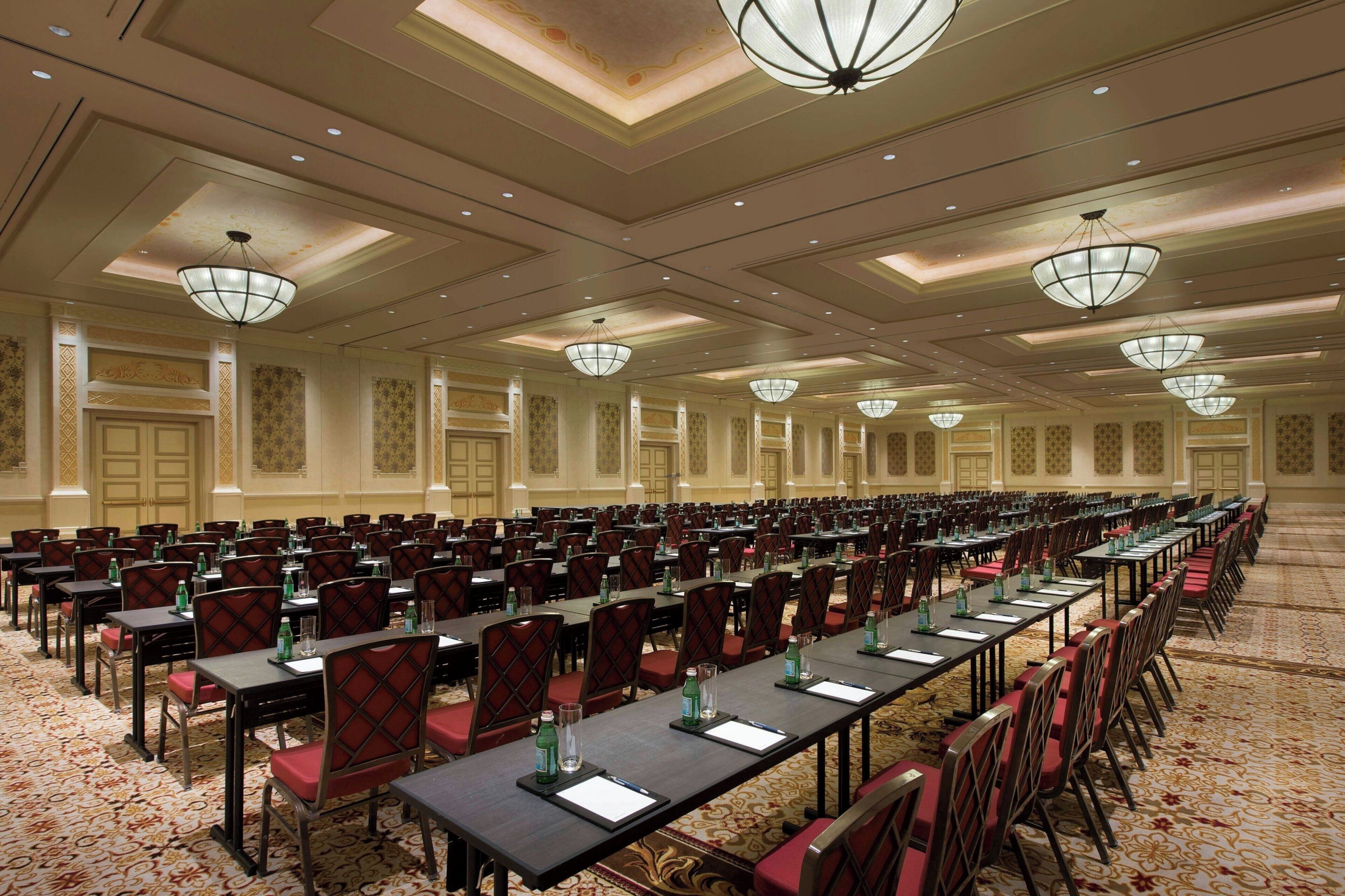 A large conference room with rows of tables and chairs, equipped with nameplates and water bottles.