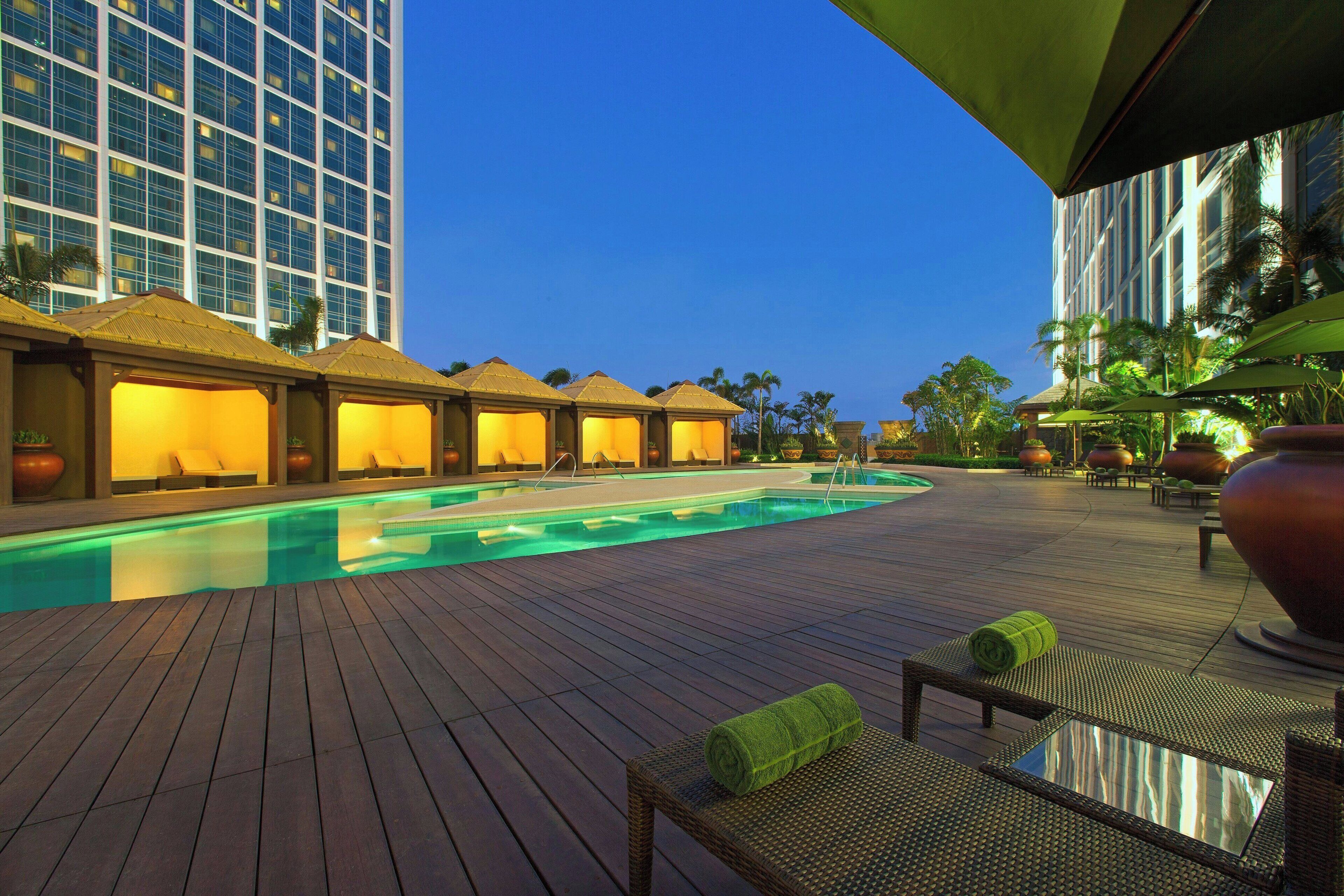 A pool area with lounge chairs and umbrellas, surrounded by buildings.