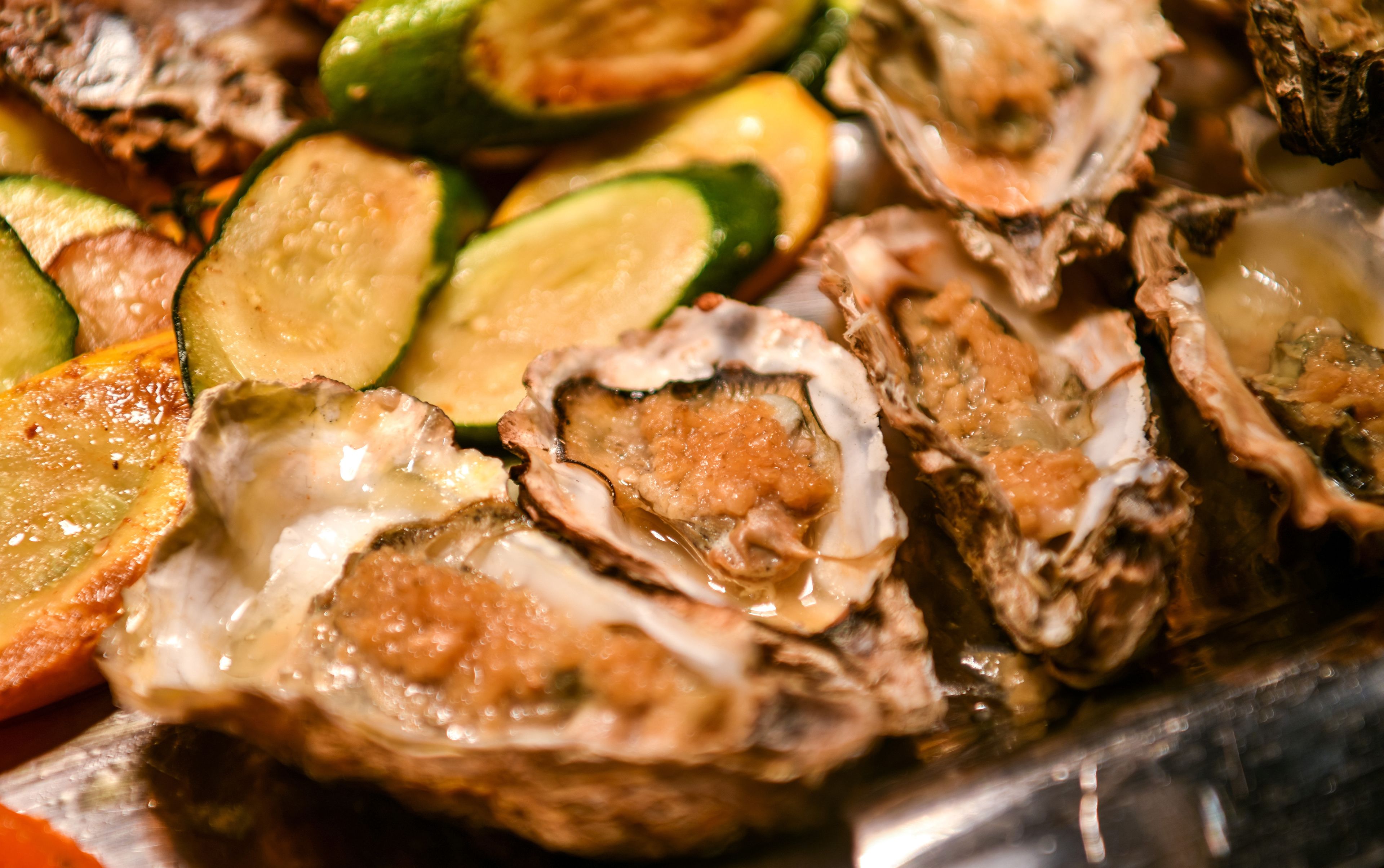 A tray of oysters with lemon slices and zucchini.