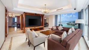 A spacious living room with a large flat-screen TV, comfortable seating, and a view of a body of water through large windows. - Four Points by Sheraton Suzhou (Suzhou)