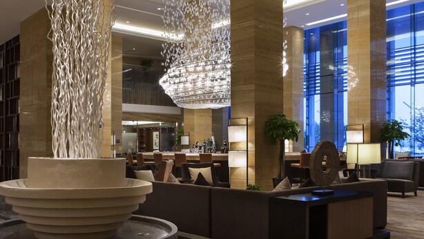 A lobby with a central water feature, seating areas, and a reception desk. - Four Points by Sheraton Suzhou (Suzhou)