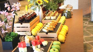 A buffet table with various food items, including cupcakes, pastries, and fruits.