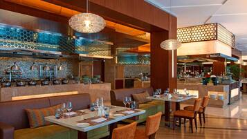 A modern restaurant with a bar area, seating arrangements, and a kitchen in the background.