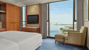 A hotel room with a large bed, a TV, a seating area, and a view of a cityscape and water. - Four Points by Sheraton Suzhou (Suzhou)