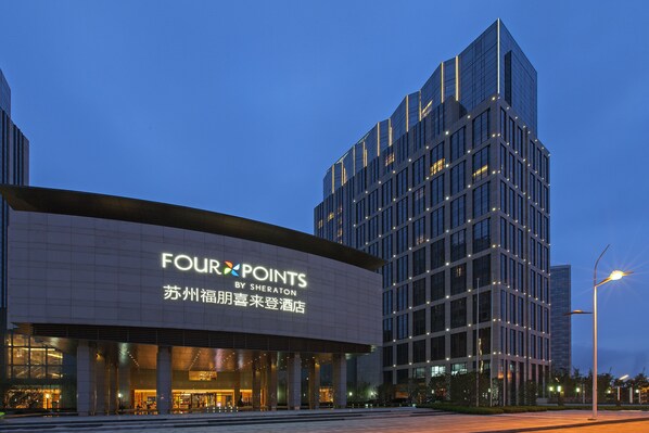 Located in the heart of the city, the hotel features a sleek glass facade and prominent signage.