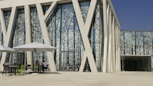 A modern building with a distinctive geometric facade, outdoor seating area with umbrellas, and a visible sign for 'ibis'. - ibis Leuven Heverlee (Leuven)