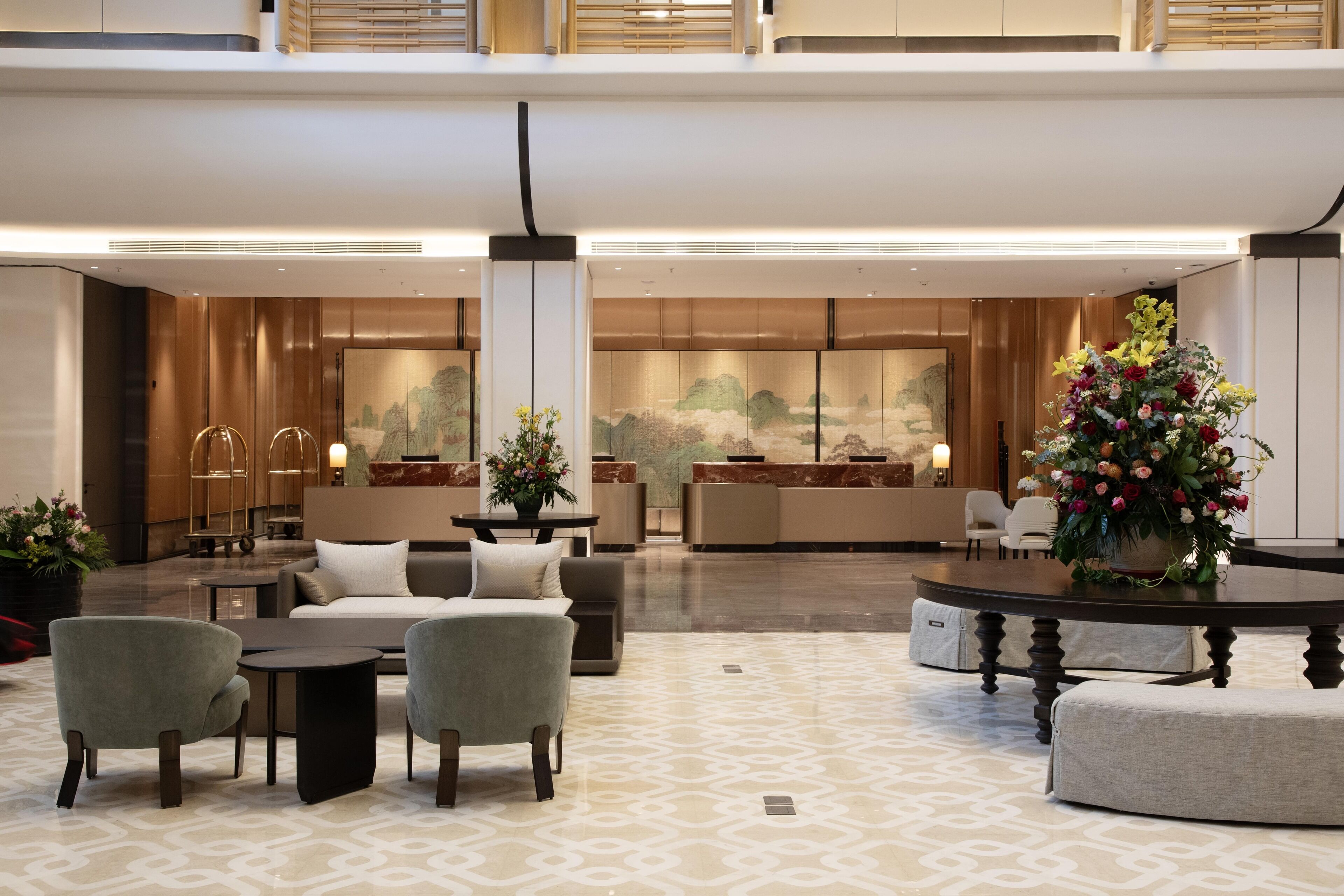 A spacious lobby with a reception desk, seating area, and decorative plants.