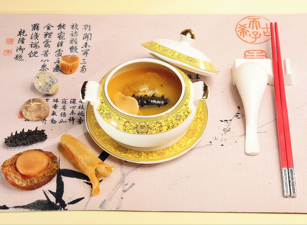 A traditional tea set with a teapot and cups, accompanied by chopsticks and a mat with calligraphy.