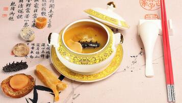 A traditional tea set with a teapot and cups, accompanied by chopsticks and a mat with calligraphy.