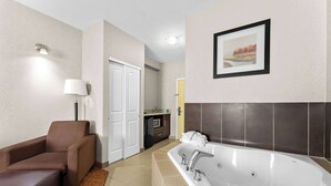 Un baño de hotel con una bañera grande, un sofá, una lámpara y un cuadro en la pared.