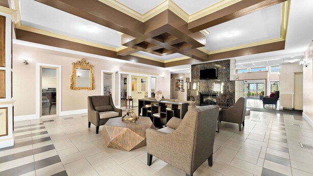 Un salón amplio con muebles modernos, un espejo grande y una cocina al fondo.