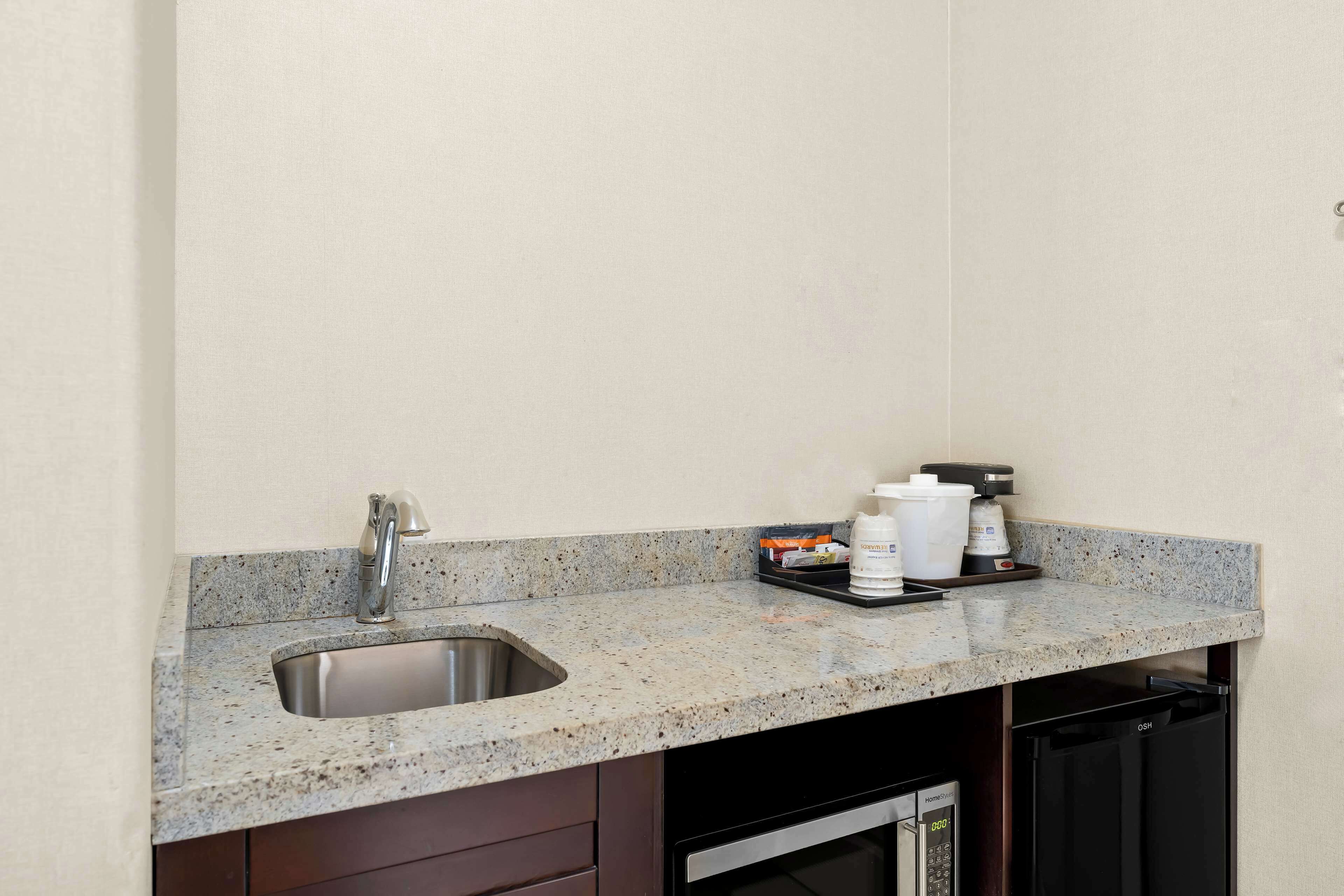 A kitchen with a granite countertop, stainless steel sink, and a black dishwasher.