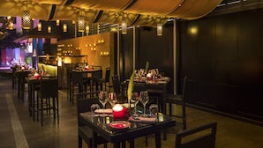 A dimly lit restaurant with tables set for dining, featuring hanging lanterns and a warm ambiance. - Hard Rock Hotel Goa Calangute (Calangute)