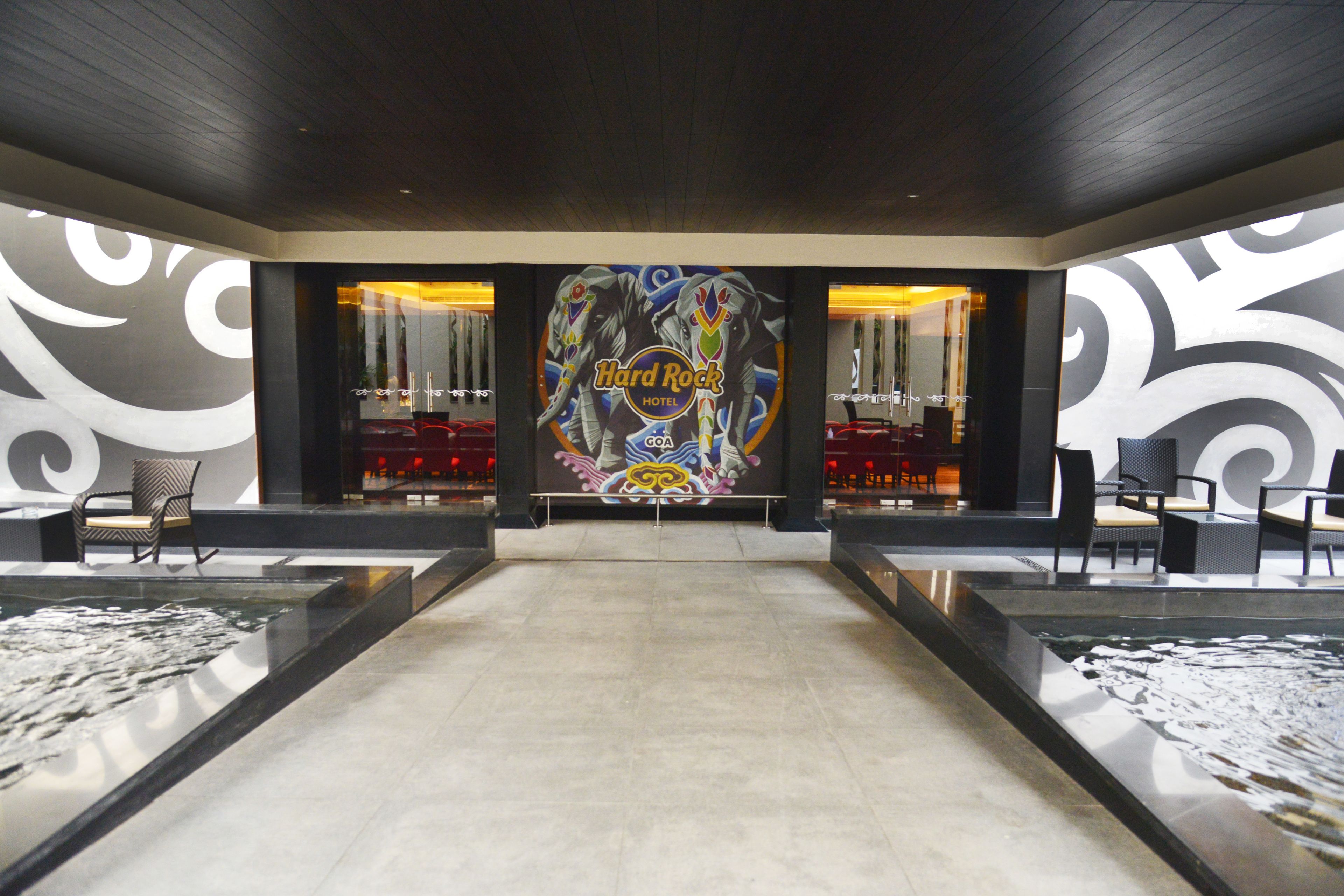 A lobby with a central Hard Rock Hotel sign, seating areas, and a water feature.