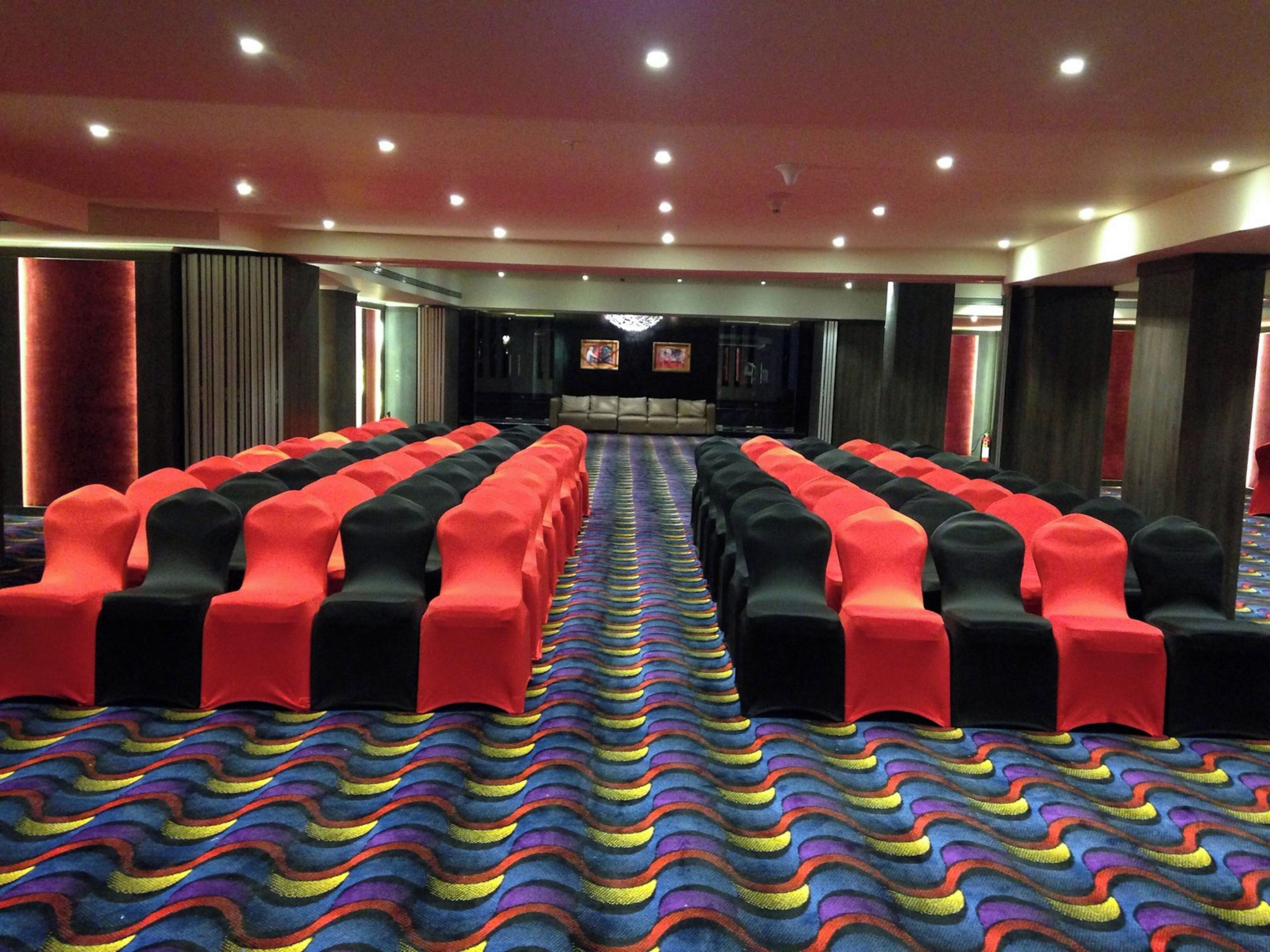 A theater with rows of seats, a stage, and a patterned carpet.