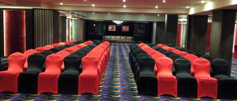 A theater with rows of seats, a stage, and a patterned carpet.