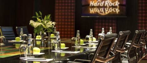 A conference table with chairs, water bottles, and a neon sign in the background.