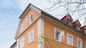 Un immeuble abritant un café appelé « Vander » au rez-de-chaussée, avec une terrasse et une enseigne.