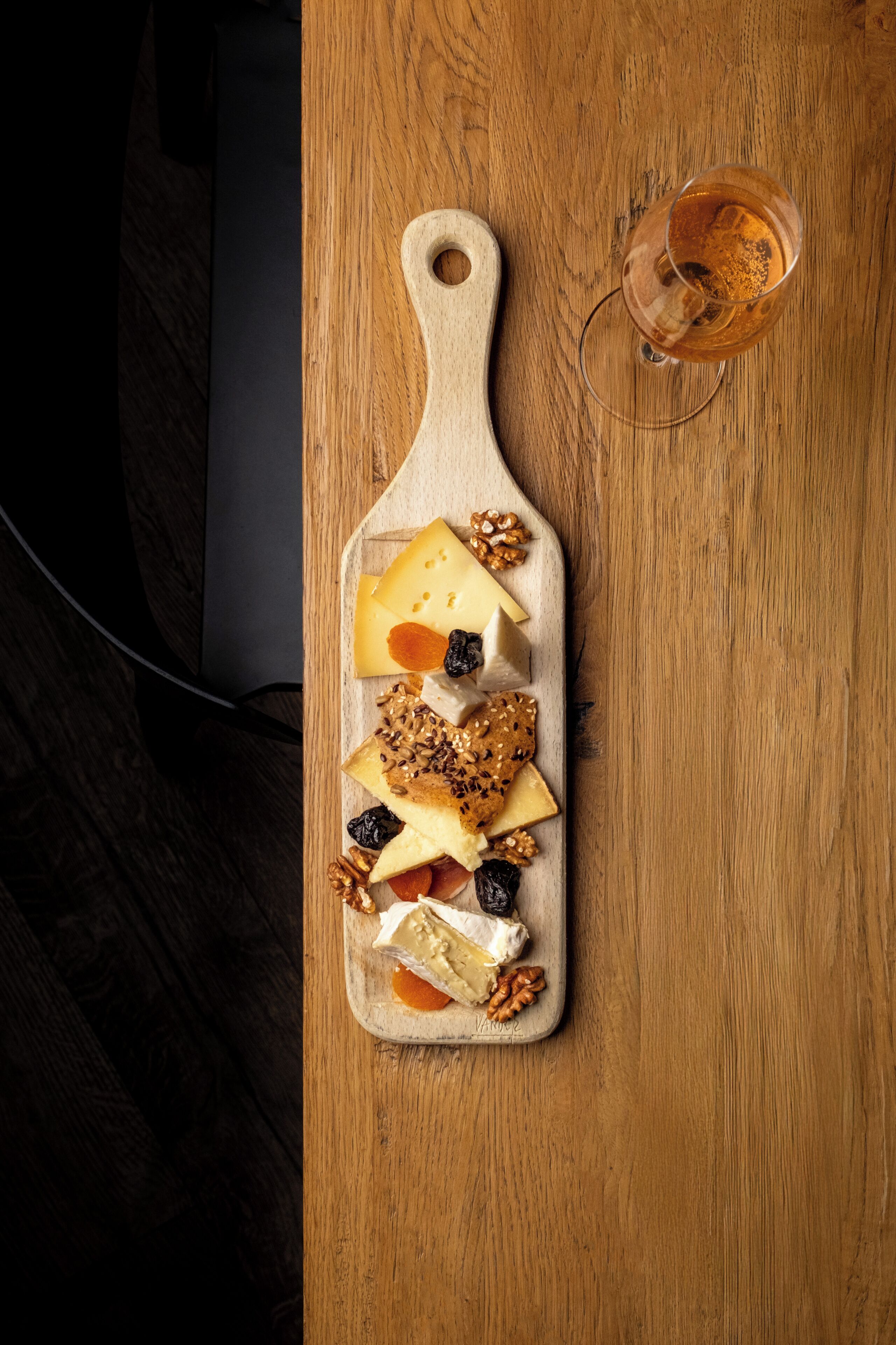 Une planche à découper en bois, avec du fromage et des noix, posée sur une table.