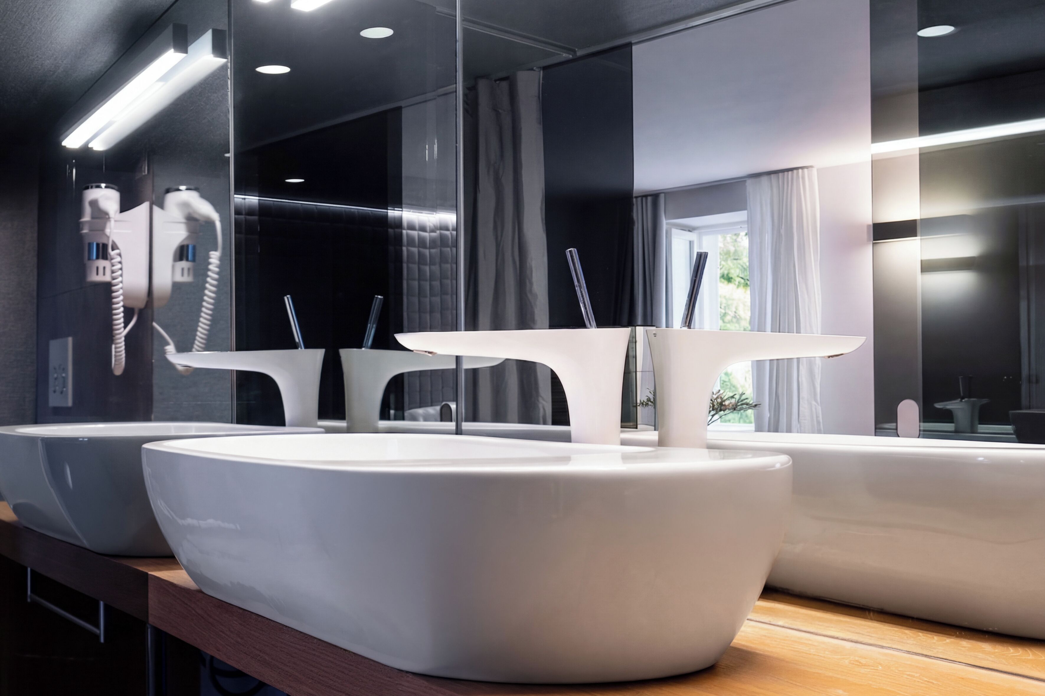 Ein modernes Badezimmer mit großen, weißen Waschbecken und einem Spiegel, der den Raum widerspiegelt.