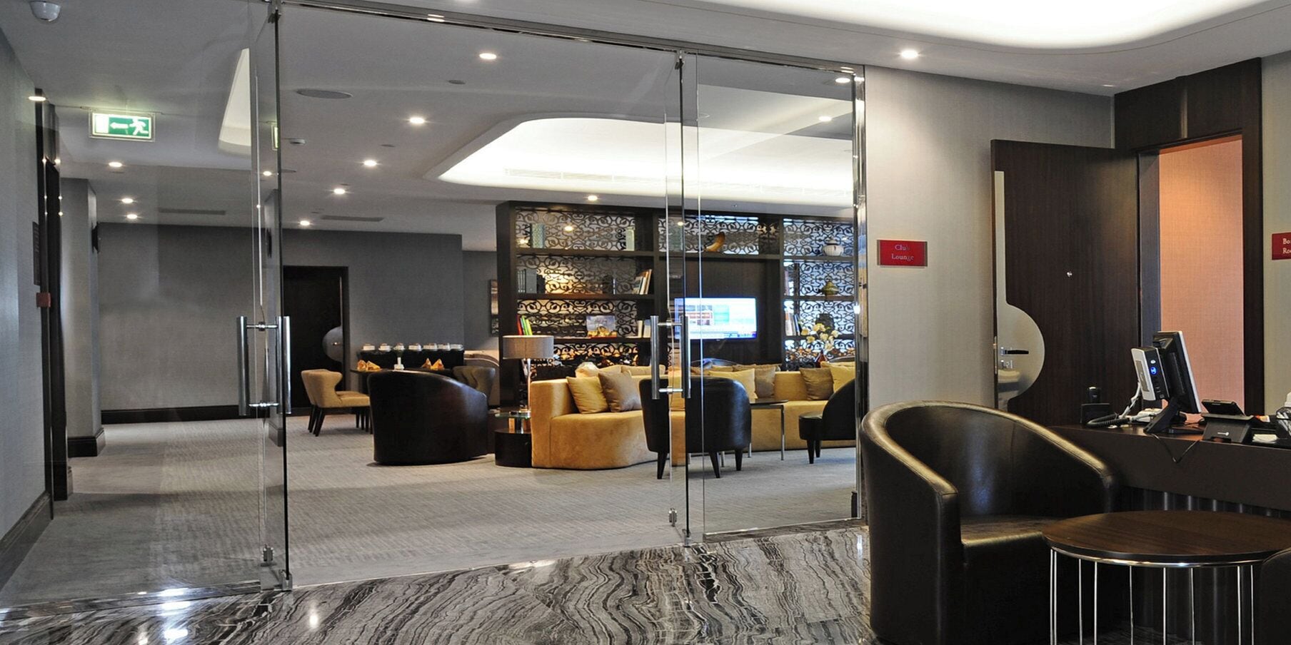 A hotel lobby with a reception desk, seating area, and a decorative wall.