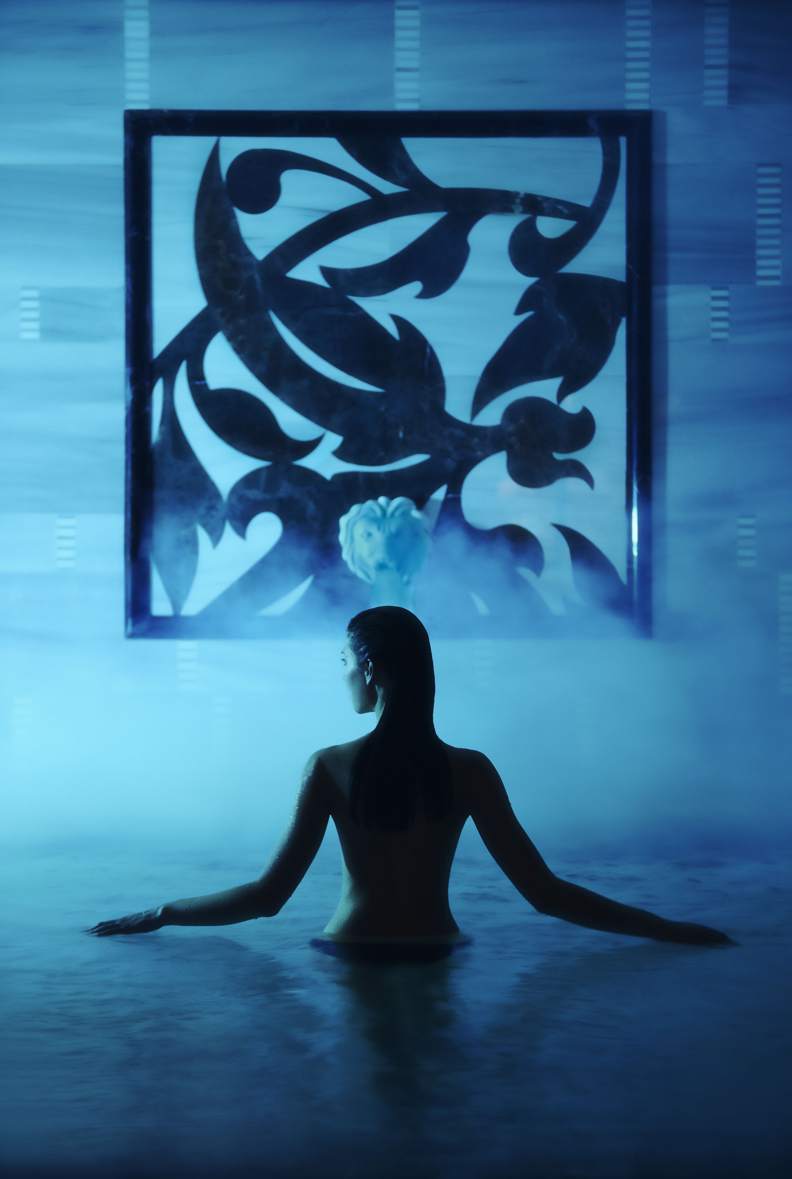 A person in a room with a large abstract artwork on the wall.