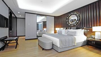 A modern hotel room with a large bed, bedside tables, a desk, and a mirror on the wall.