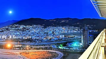 Paisagem urbana noturna com um edifício em destaque e uma linha de trem.