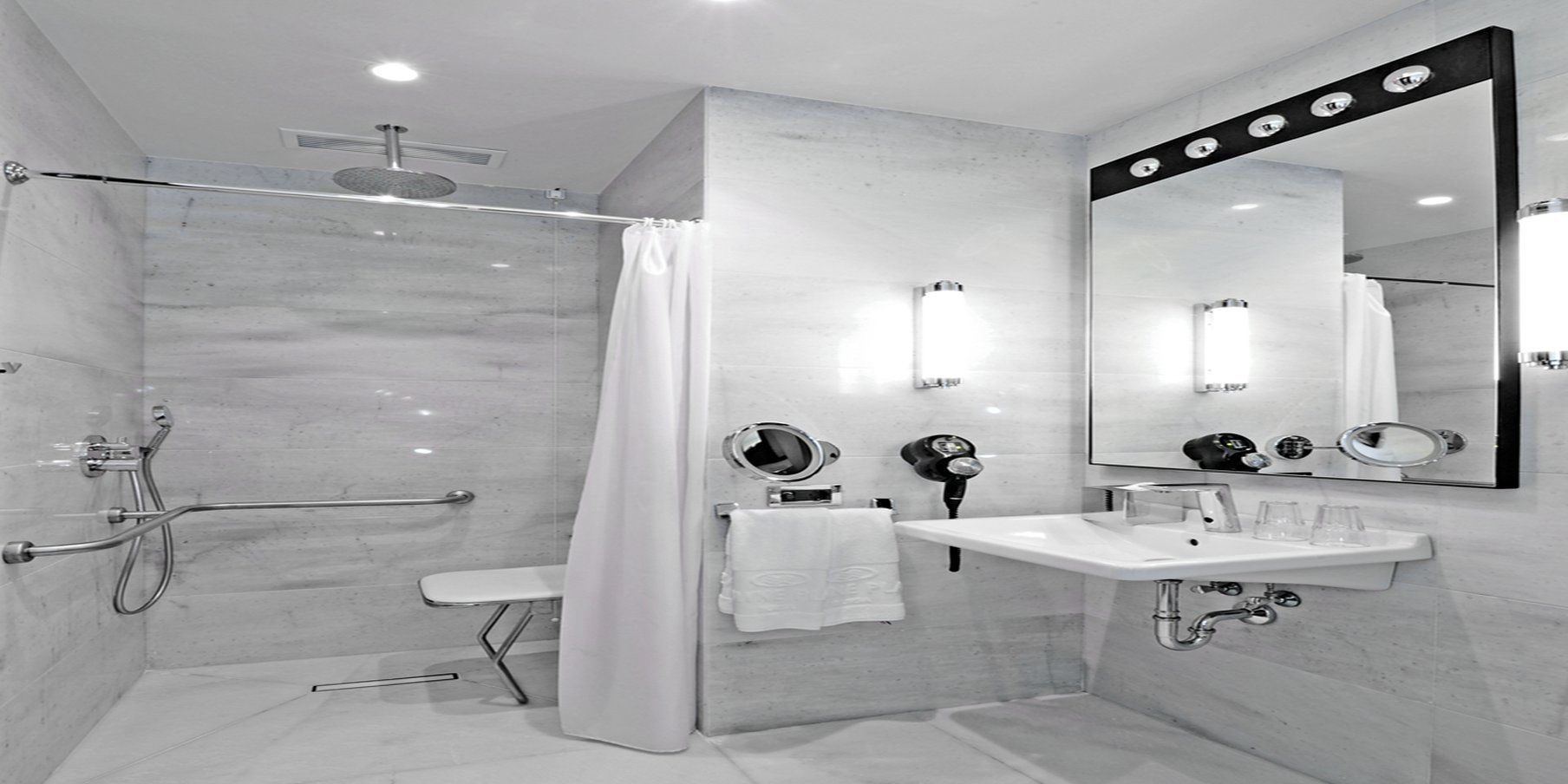 Un baño moderno con ducha a nivel, tocador con espejo y secador de pelo.