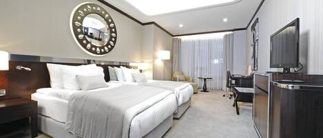A hotel room with a large bed, a desk, a TV, and a mirror.