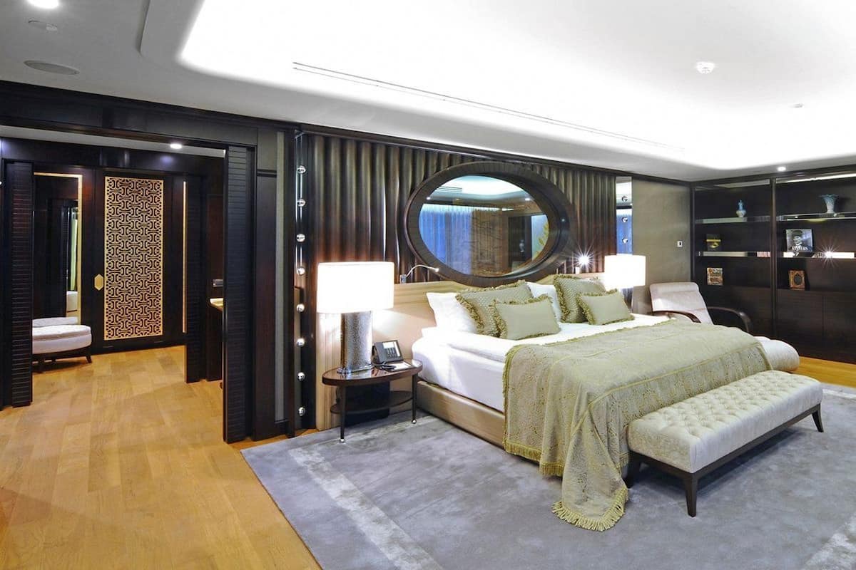 A modern bedroom with a large bed, bedside tables, a desk, and a mirror.