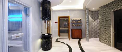 A modern interior with a glass door leading to a bathroom, a marble column, and a patterned wall.