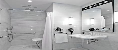 A modern bathroom with a walk-in shower, a vanity with a mirror, and a hairdryer.