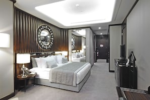 A modern hotel room with a large bed, a bedside table with a lamp, a mirror, and a TV. - Crowne Plaza Bursa Convention Center & Thermal Spa by IHG (Bursa)