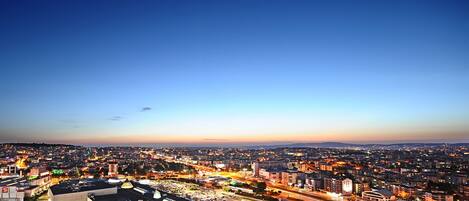 A cityscape at dusk with illuminated buildings and a clear sky.