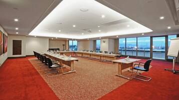 A conference room with a long table, chairs, a projector, and a large window with a view.